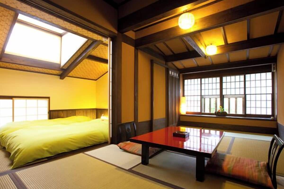 Una habitación japonesa tradicional con suelo de tatami, una mesa baja y una cama con edredón amarillo.