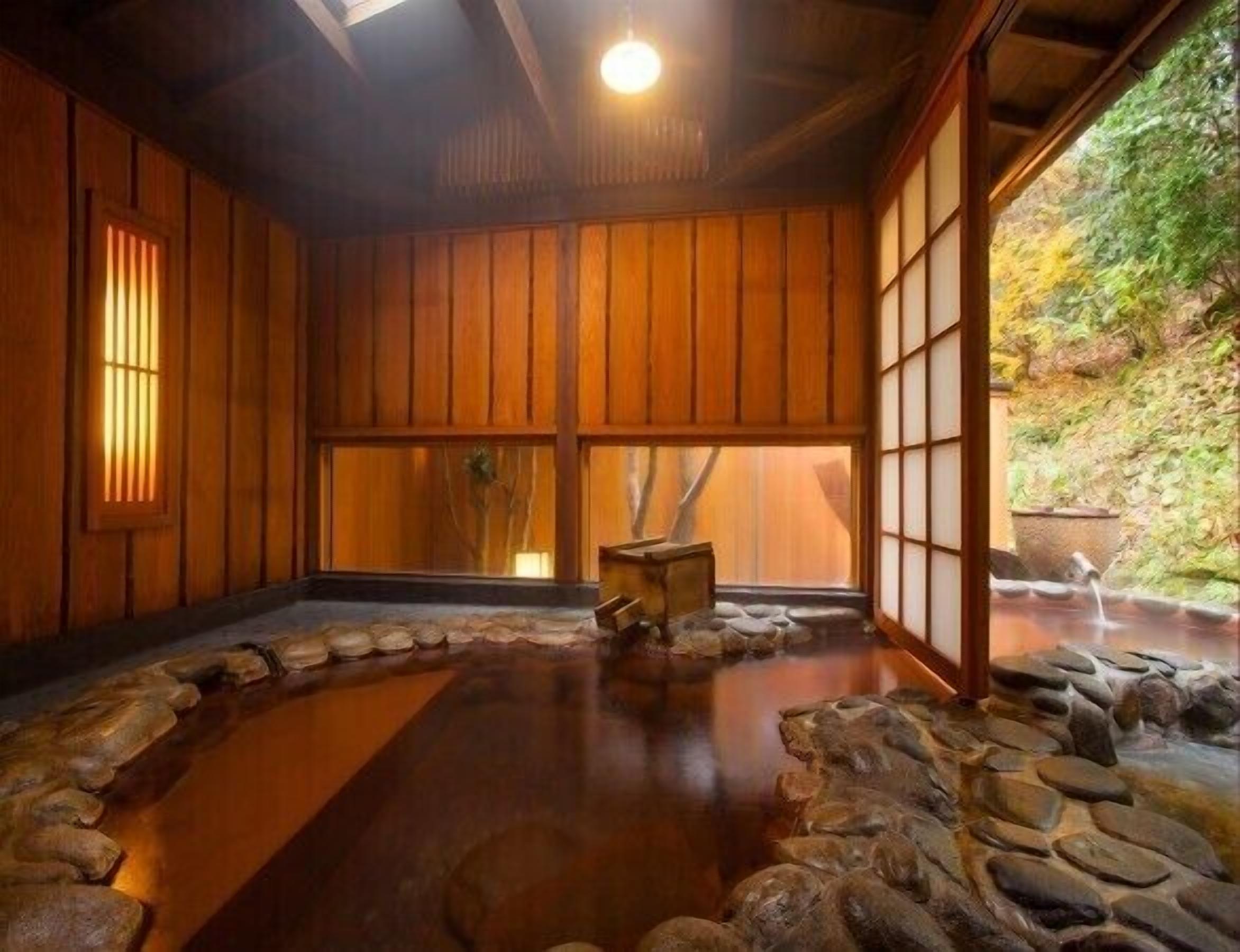 A traditional Japanese room with tatami flooring, wooden sliding doors, and a stone water feature.