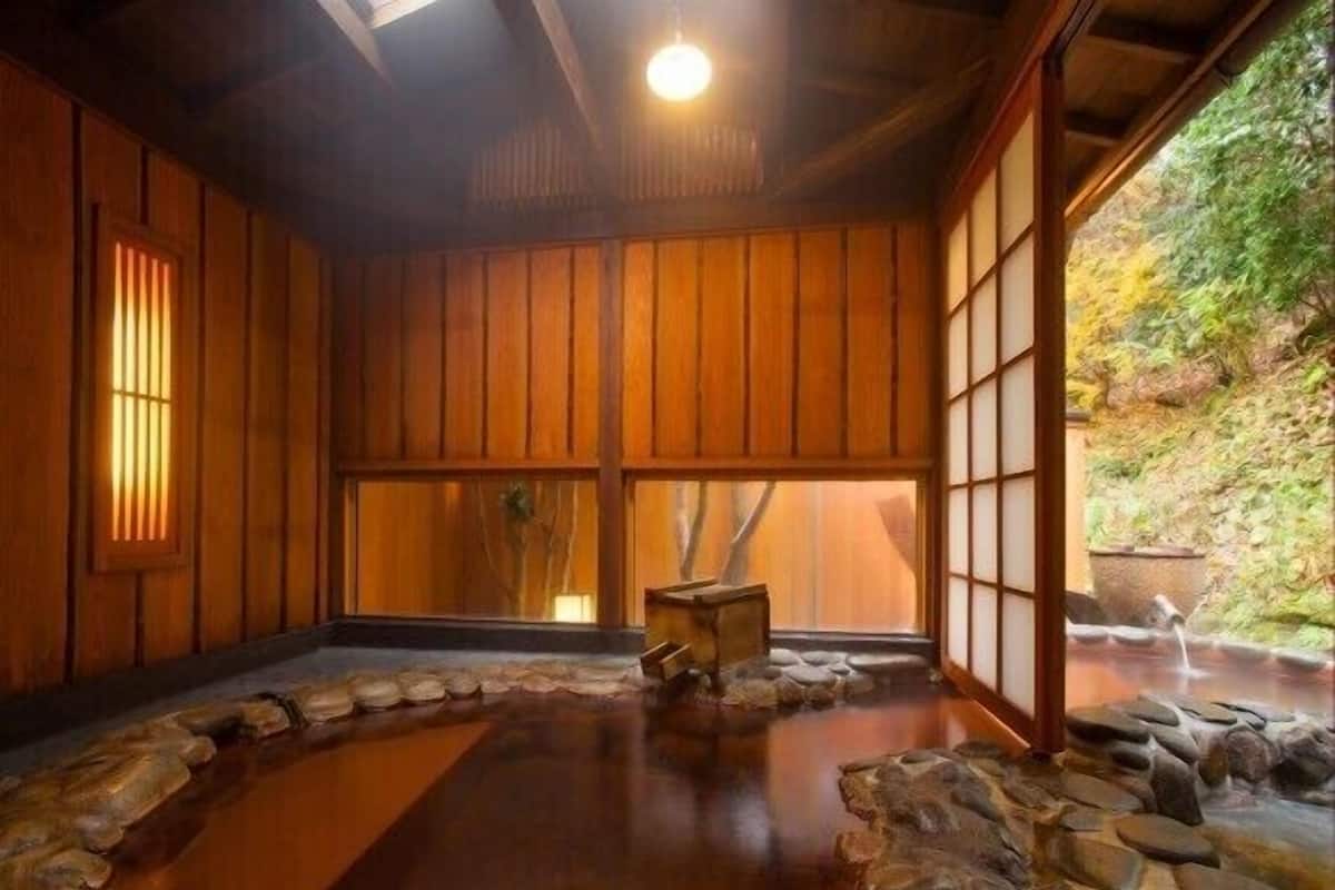 Una habitación japonesa tradicional con suelo de tatami, puertas correderas de madera y una fuente de agua de piedra.