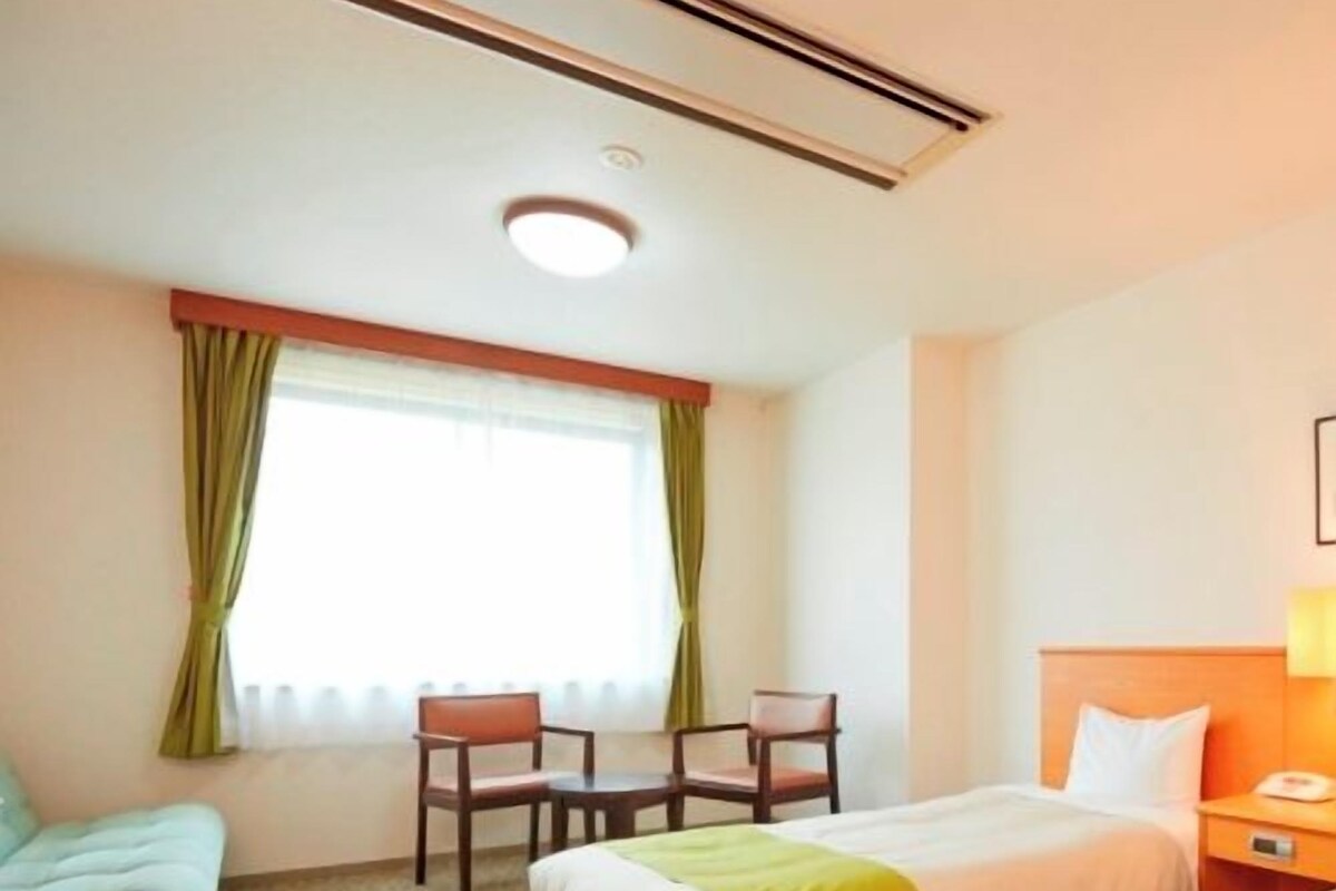 Une chambre d’hôtel avec deux lits, un canapé, un bureau et une chaise.