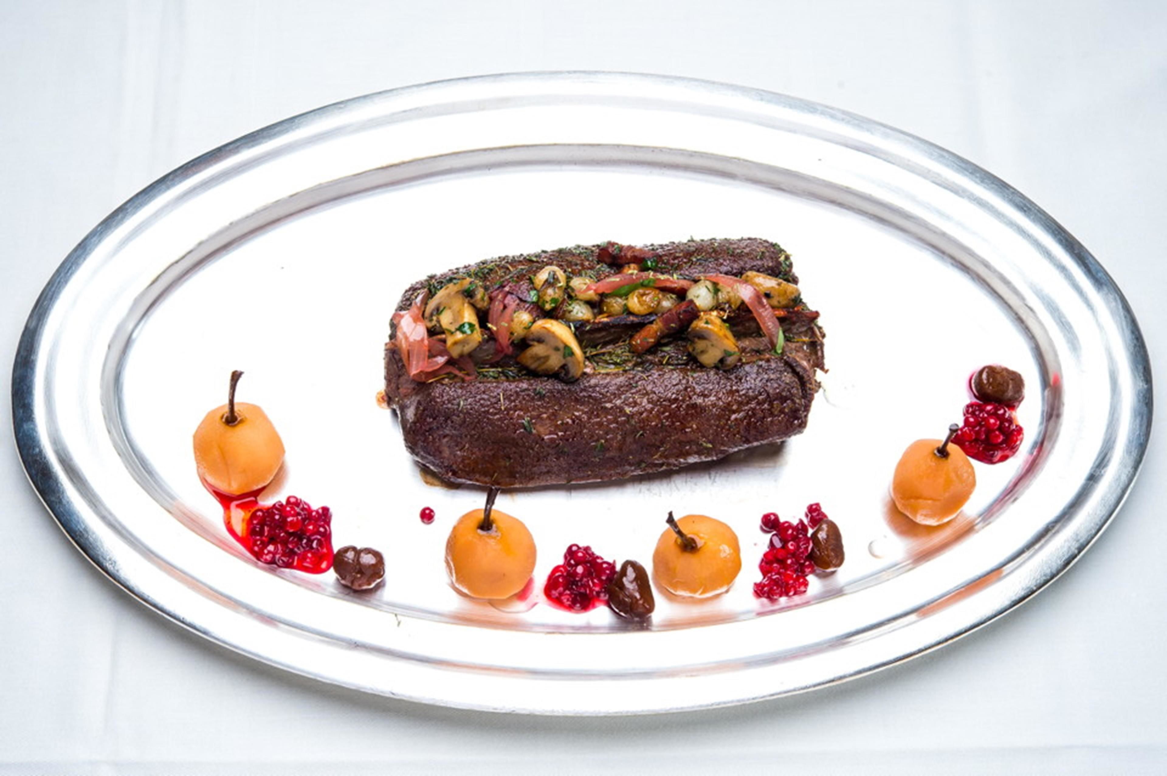 Een steak met groenten en bessen op een bord.