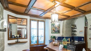 Un espace bar avec des tabourets en bois, un comptoir doté d’un tableau noir servant de menu, et un grand miroir accroché au mur.
