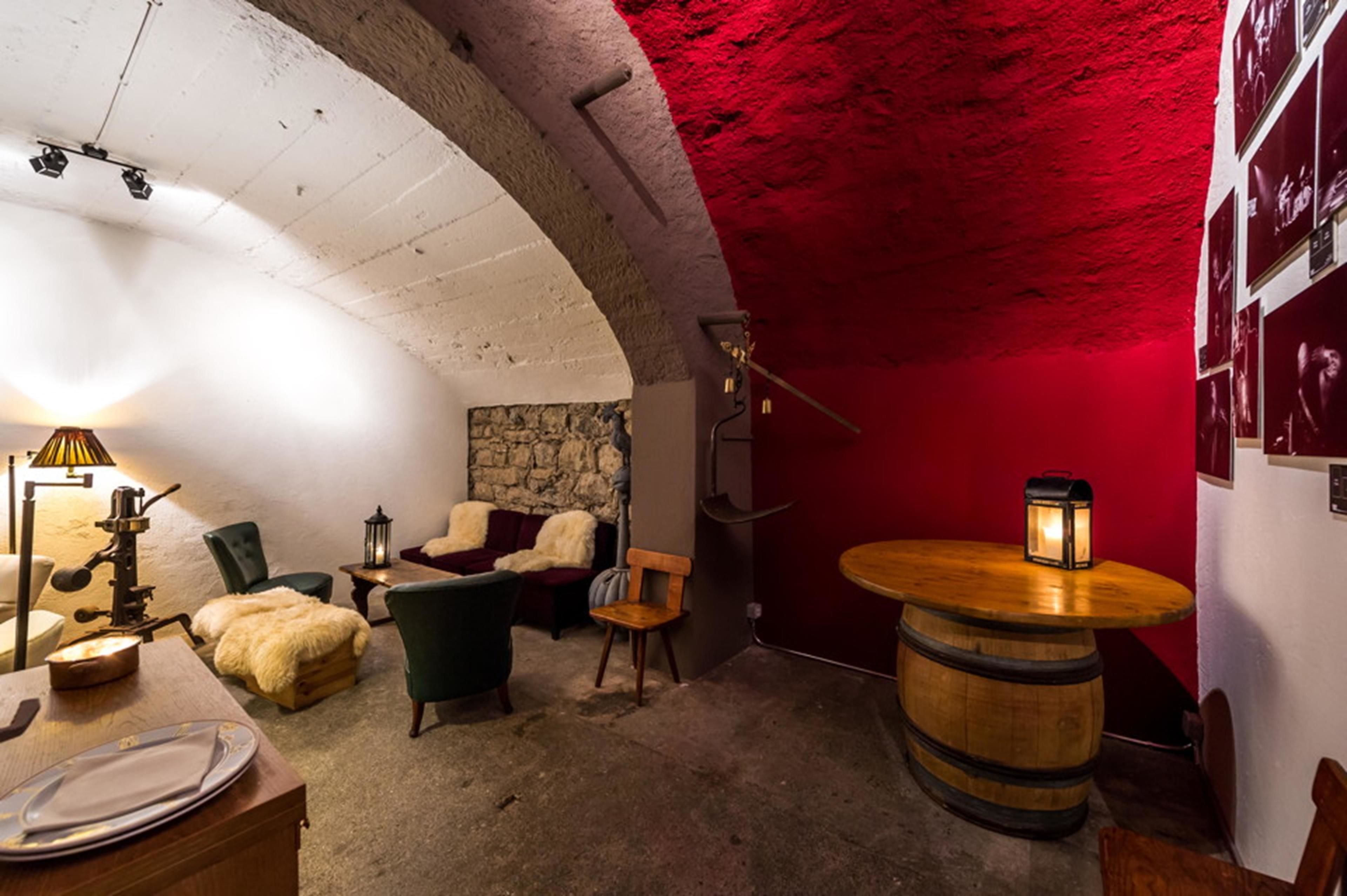 Um quarto acolhedor com parede de pedra, uma mesa de madeira em formato de barril e teto vermelho.