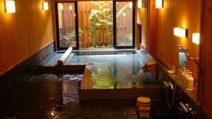A spa room with a hot tub, wooden walls, and a view of greenery outside. - Kurokawa Onsen Wafu Ryokan Misato (Minamioguni)