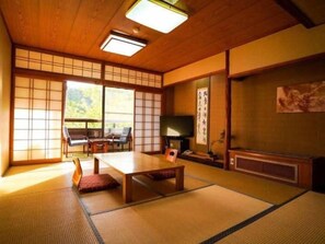 Ein traditioneller japanischer Raum mit Tatami-Boden, einem niedrigen Tisch und einem Fernseher.