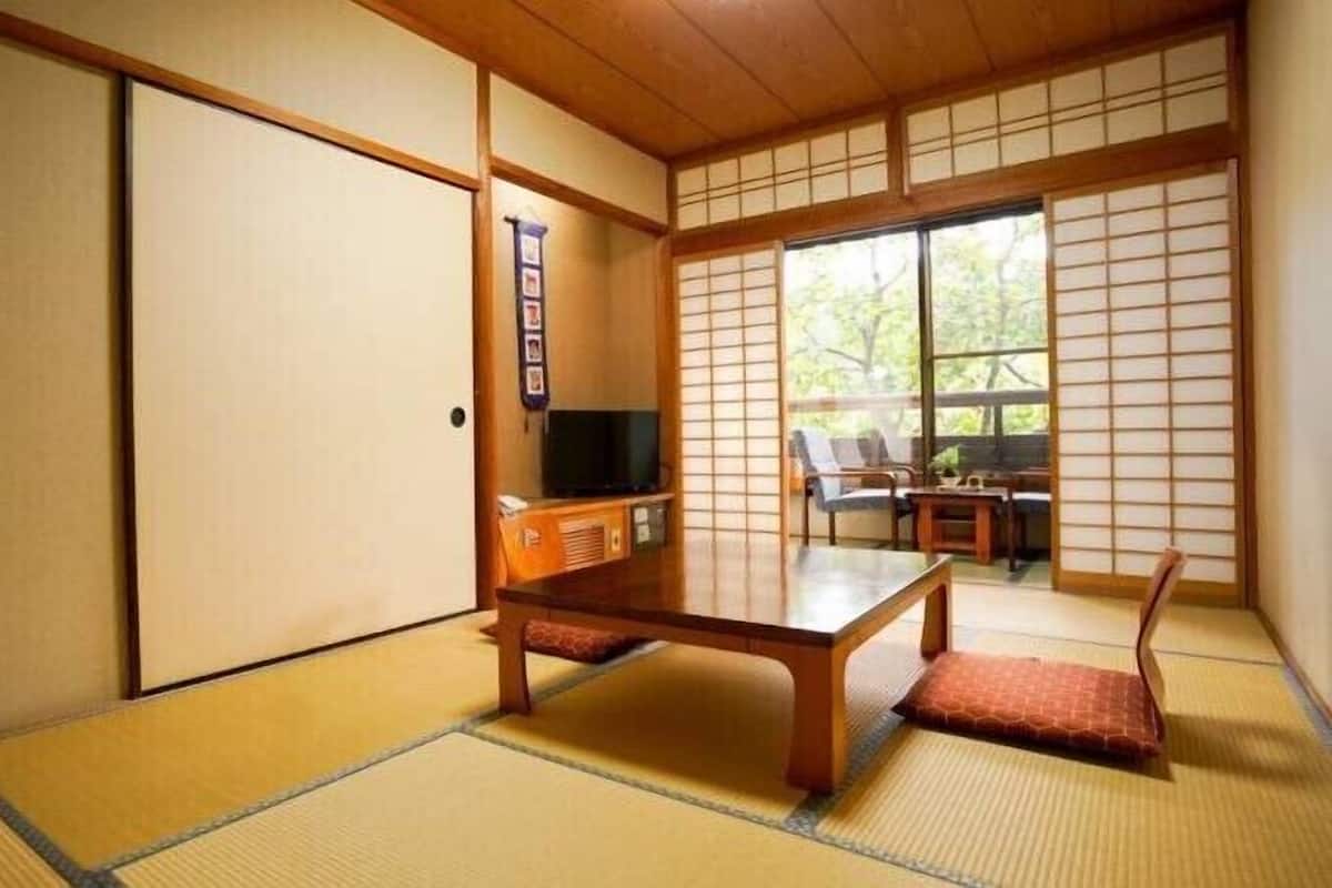 A traditional Japanese room with tatami flooring, a low wooden table, a television, and sliding shoji doors.