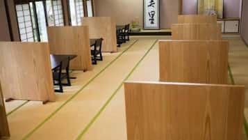 A traditional Japanese room with tatami flooring, low wooden partitions, and a tatami mat pattern.