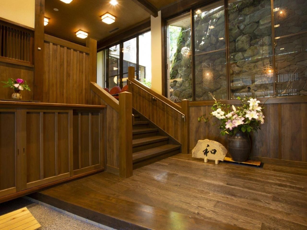 A wooden staircase with a handrail leading to a landing area with a small table and a vase of flowers.