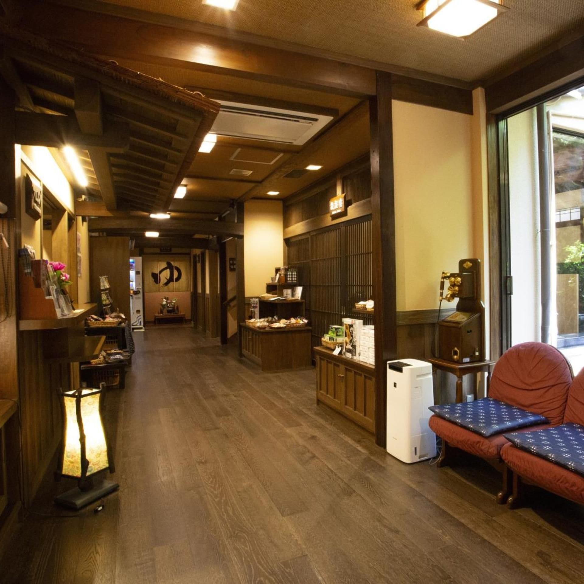 A hotel lobby with a reception desk, seating area, and a large window.
