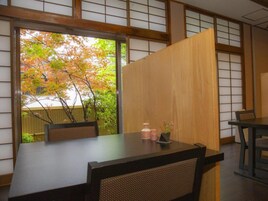 Una habitación japonesa tradicional con suelo de tatami, una mesa baja y puertas correderas.