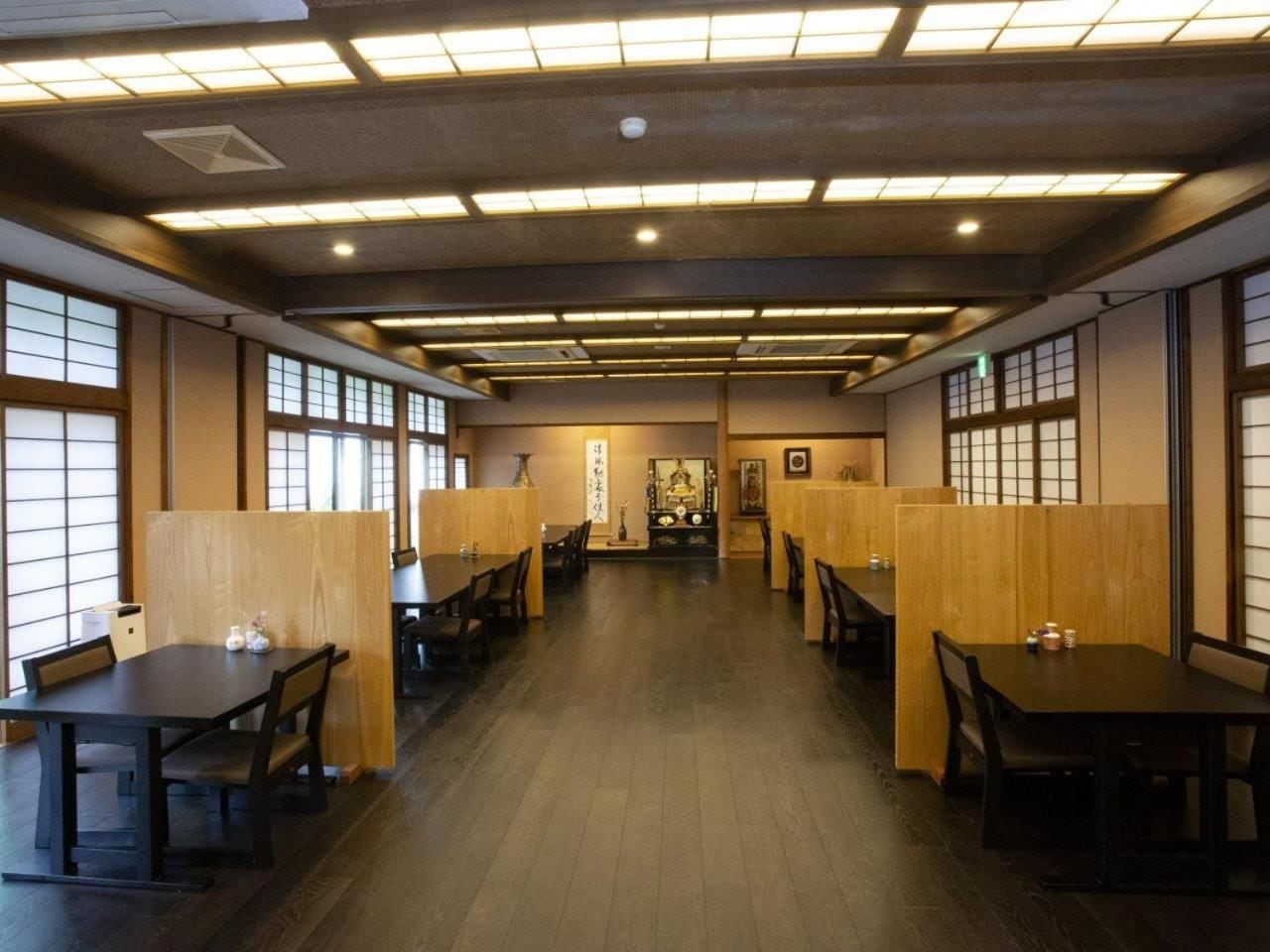 A traditional Japanese restaurant interior with tatami mat flooring, low wooden tables, and shoji screens.
