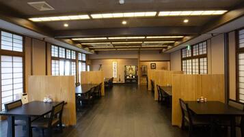 A traditional Japanese restaurant interior with tatami mat flooring, low wooden tables, and shoji screens.