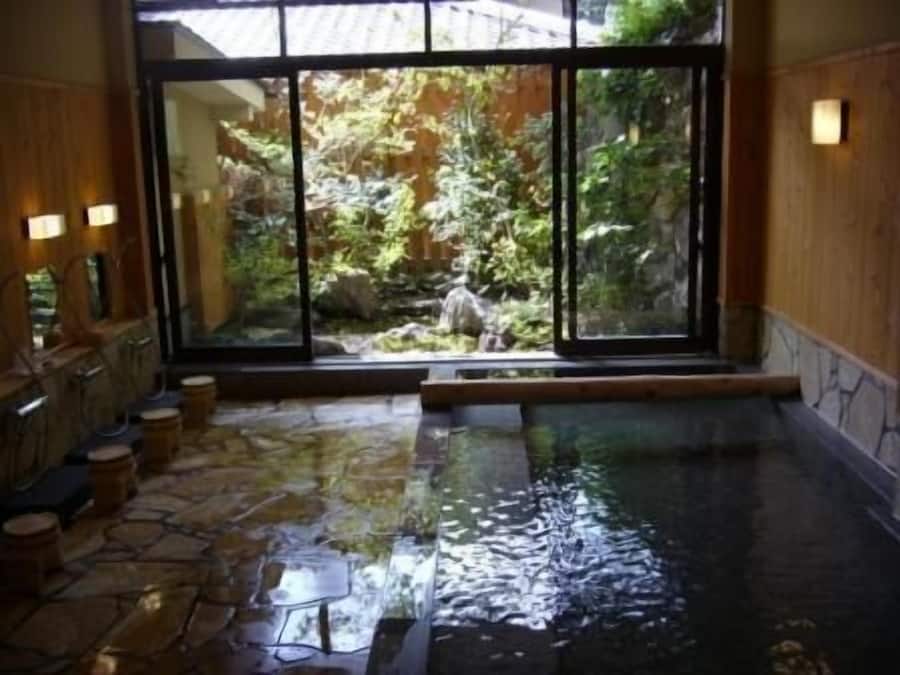 Una piscina interior con suelo de piedra y vistas a un jardín rocoso a través de amplios ventanales.