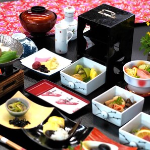 Diversos alimentos y platos dispuestos en una mesa con un fondo floral.