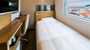A hotel room with a bed, a desk with a computer, a TV, and a window with a city view. - Sekishuu no Yu Super Hotel Gotsu Ekimae (Gotsu)