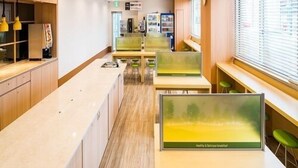 A modern, well-lit office space with long tables and green chairs, featuring a large window with blinds and a view of the city. - Sekishuu no Yu Super Hotel Gotsu Ekimae (Gotsu)