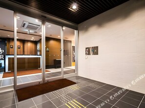 A modern interior with a reception desk, glass doors, and a patterned floor. - Sekishuu no Yu Super Hotel Gotsu Ekimae (Gotsu)