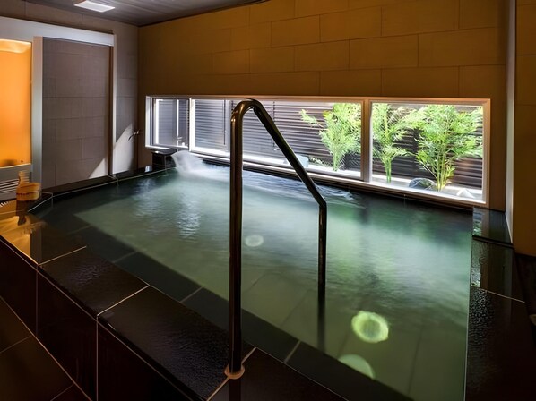 Una piscina interior con barrera de vidrio y vistas a zonas verdes.