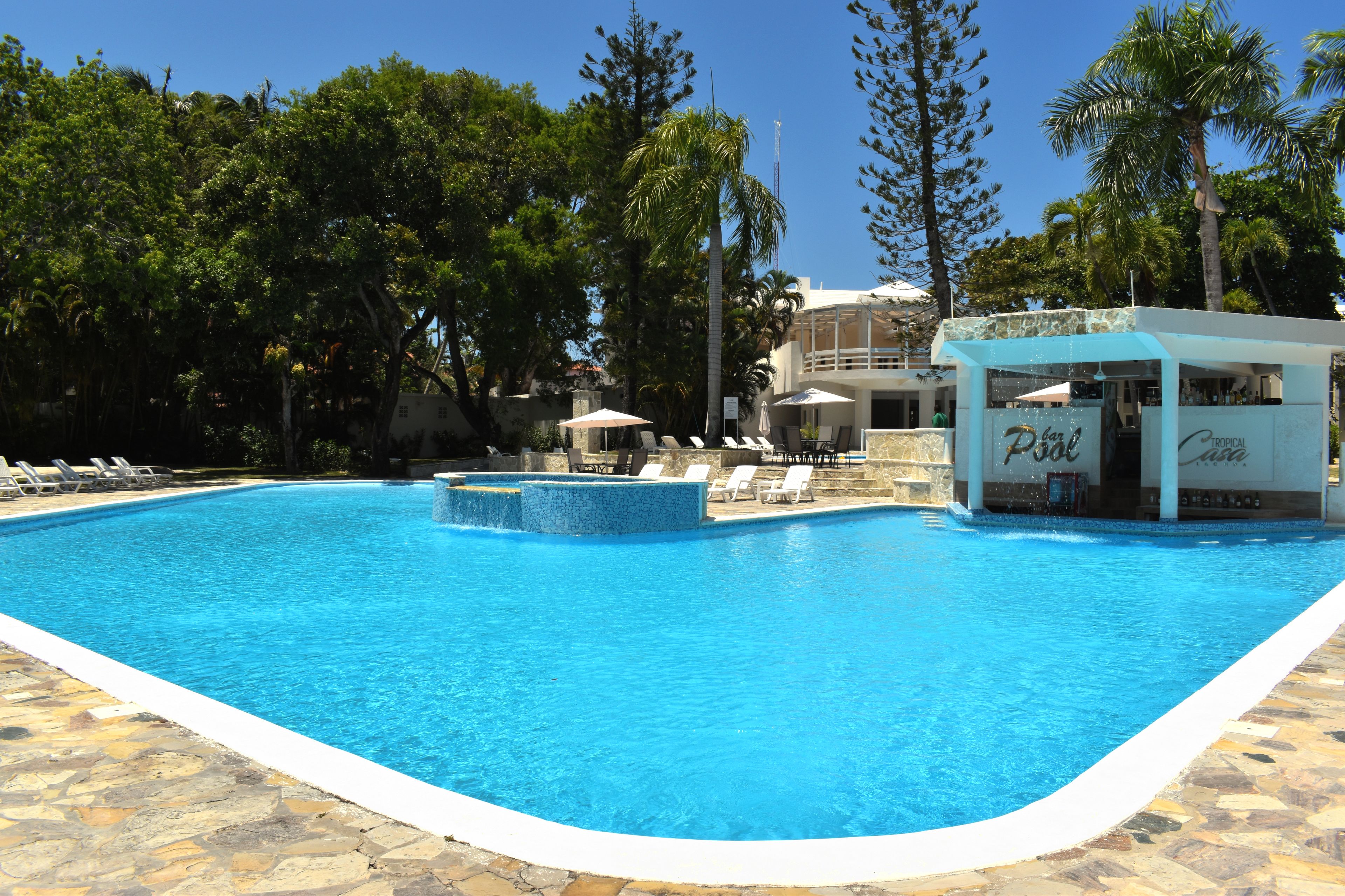 Une piscine avec des chaises longues et un espace bar.