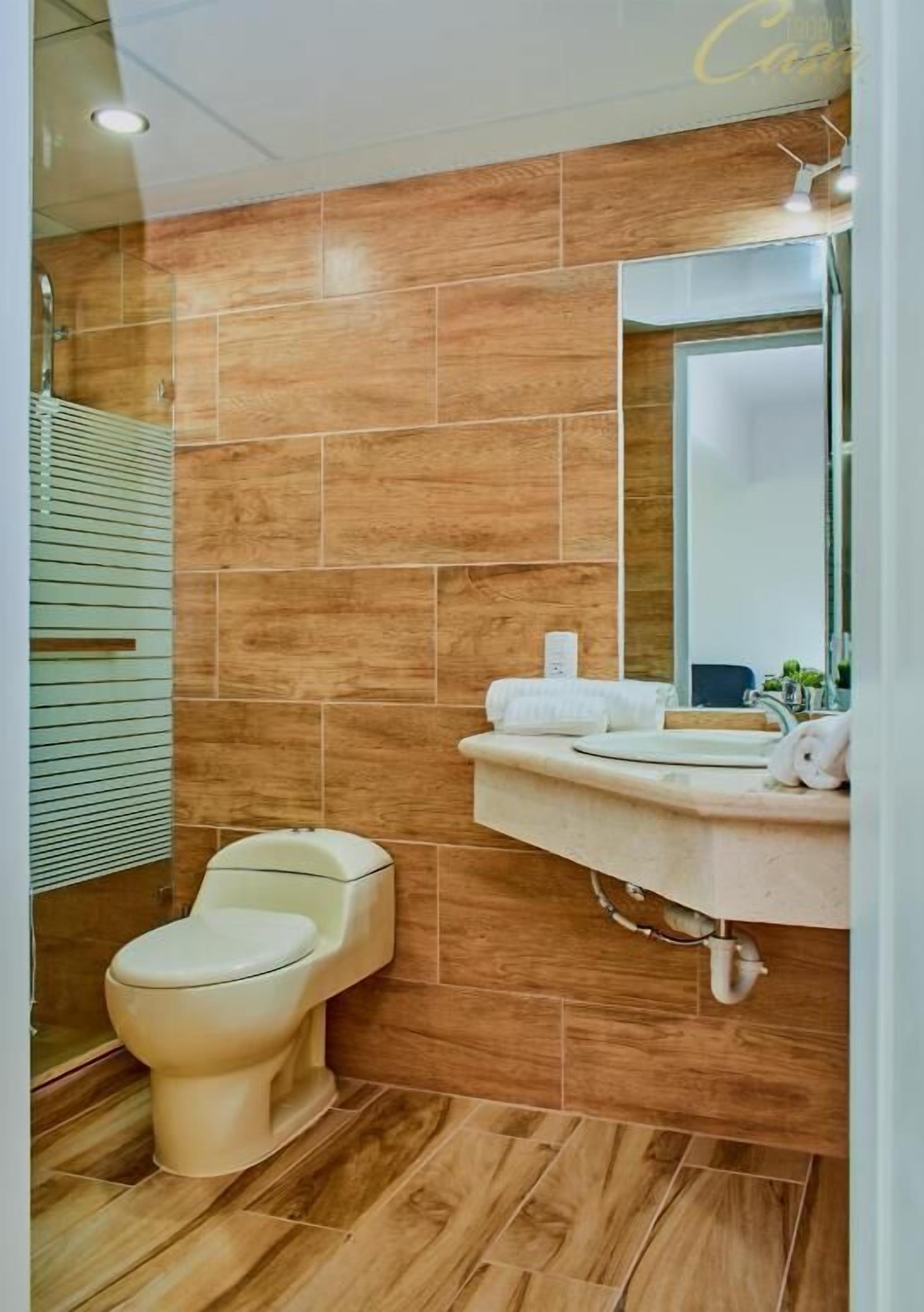 A bathroom with a toilet, sink, and mirror.