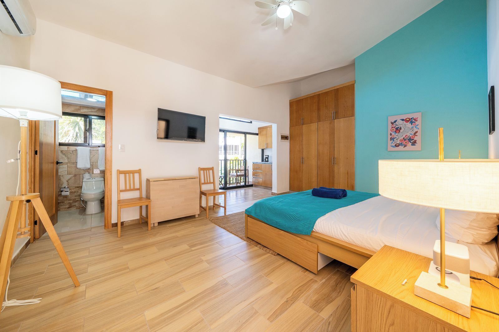 A bedroom with a bed, a desk, a chair, a television, and a wardrobe.