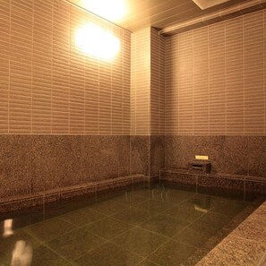 A spa area with a rectangular hot tub, tiled walls, and a marble floor. - AB Hotel Toyota Motomachi (Toyota)