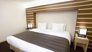 A hotel room with a large bed, wooden headboard, two bedside tables, and a nightstand with a lamp. - Hakone Suishoen (Hakone)