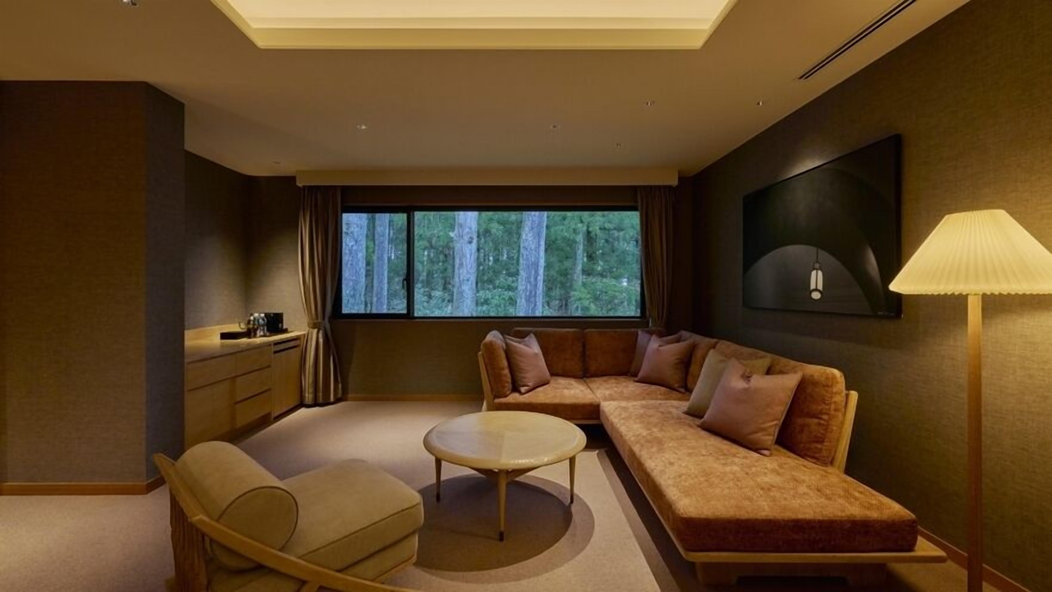 A modern living room with a sofa, armchair, coffee table, and a lamp.