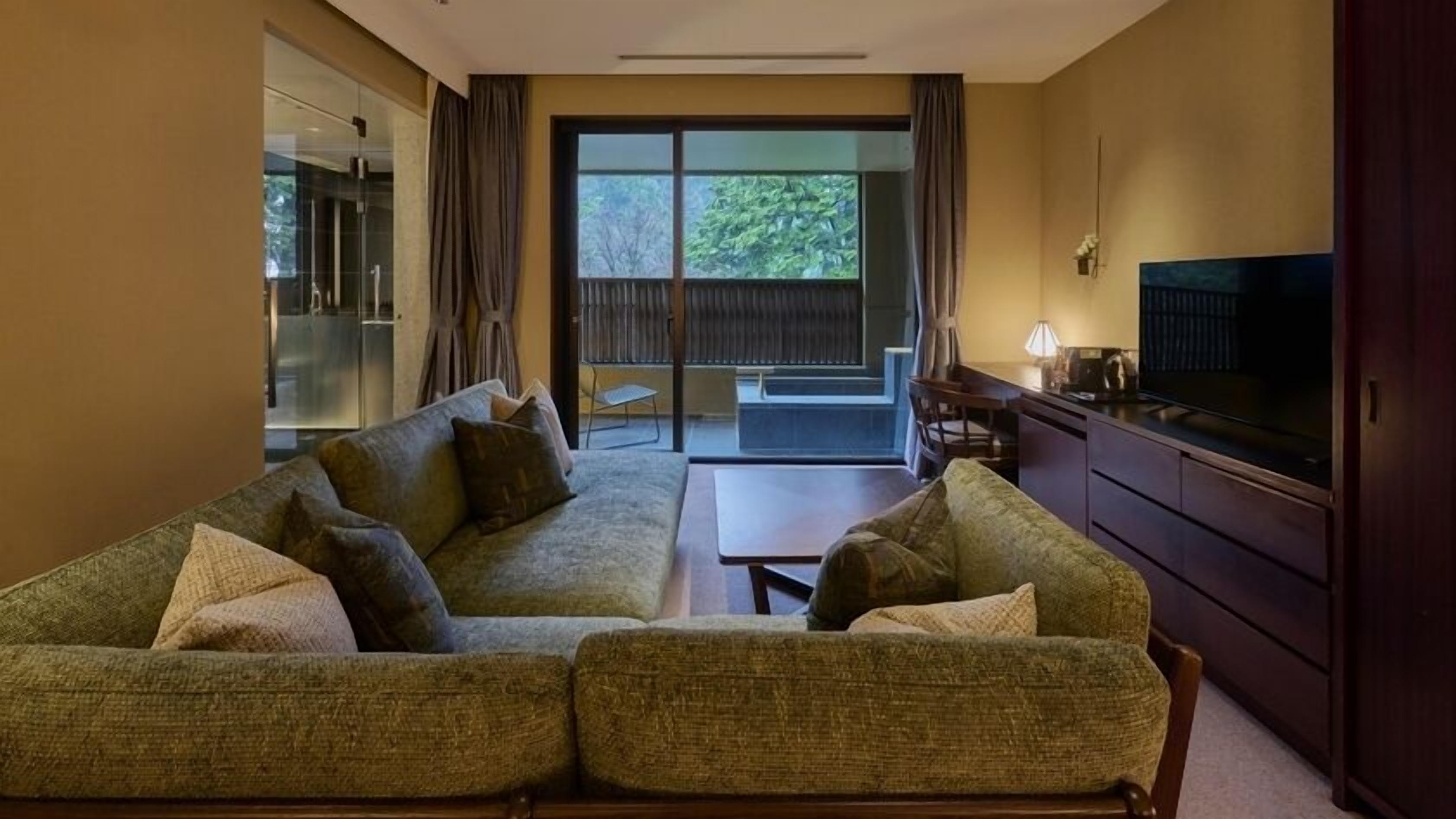A living room with a sofa, a television, and a sliding glass door leading to a balcony.