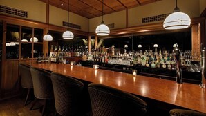 A bar with wooden ceiling and pendant lights, bar stools, and a variety of bottles and glasses. - Hakone Suishoen (Hakone)