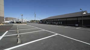 A parking lot with marked spaces, a building with a flat roof, and a clear sky. - Hotel Econo Taki (Taki)