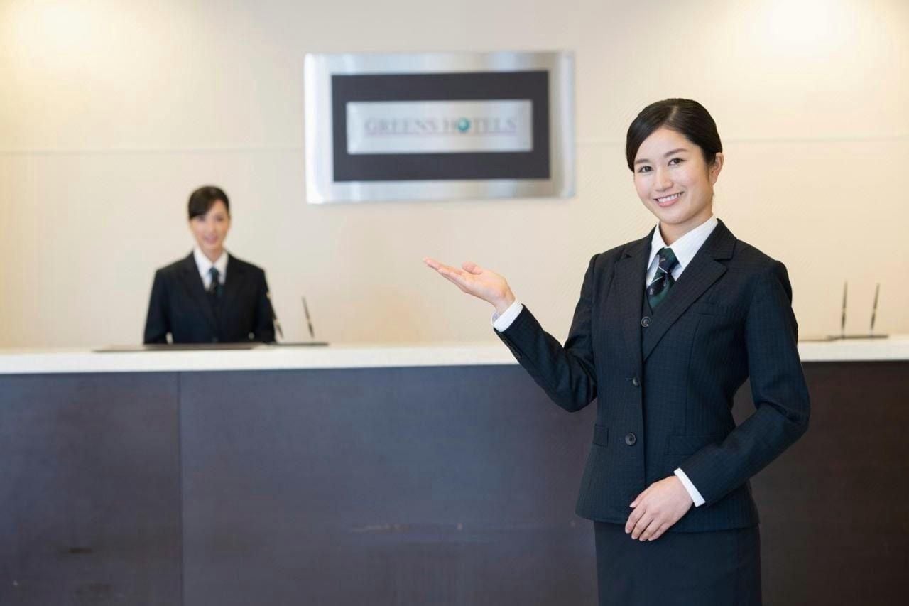 A hotel reception area with a reception desk and a framed sign above it.