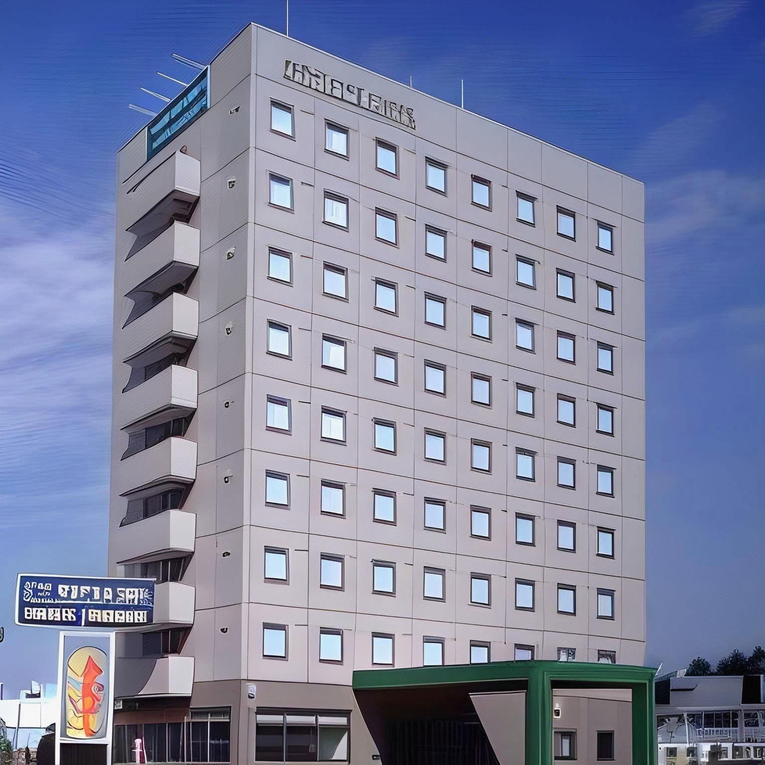 A multi-story hotel building with a modern architectural design, featuring a uniform facade with evenly spaced windows and balconies on the upper floors.
