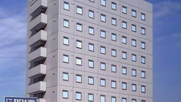 A multi-story hotel building with a modern architectural design, featuring a uniform facade with evenly spaced windows and balconies on the upper floors.