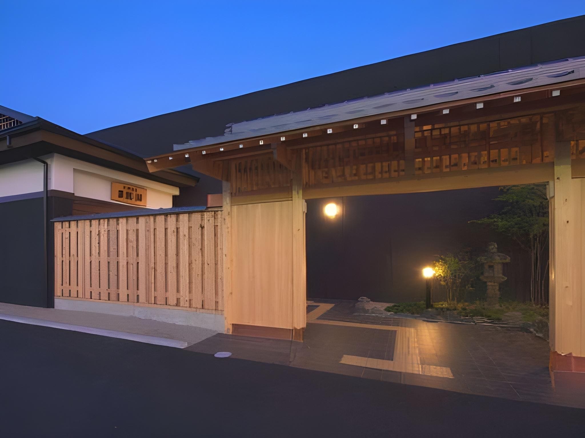 A traditional Japanese gate with a wooden structure and a modern building in the background.