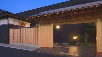 A traditional Japanese gate with a wooden structure and a modern building in the background.