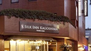 Het uiterlijk van Silk Inn Kagoshima Hotel & Spa, met een bakstenen gevel en een bord met verlichte letters.