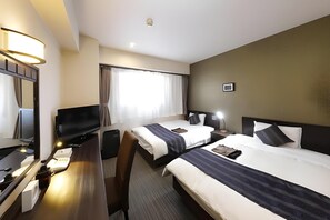 A hotel room with two beds, a desk with a computer, a TV, and a large window with curtains.