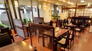 Een restaurant met houten meubels, een traditioneel Japans interieur en uitzicht op groen.