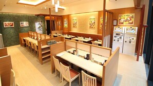 Un interior de restaurante con cabinas, mesas y una barra.
