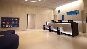 Una moderna zona de recepción con mostrador, sillas y una pantalla mural.
