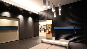 Un área de recepción moderna con mostrador, zona de estar y vista al vestíbulo.