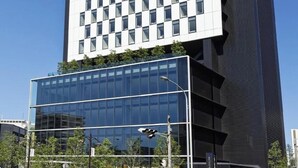 Un edificio alto con fachada a cuadros y una sección inferior de vidrio, presumiblemente un hotel.
