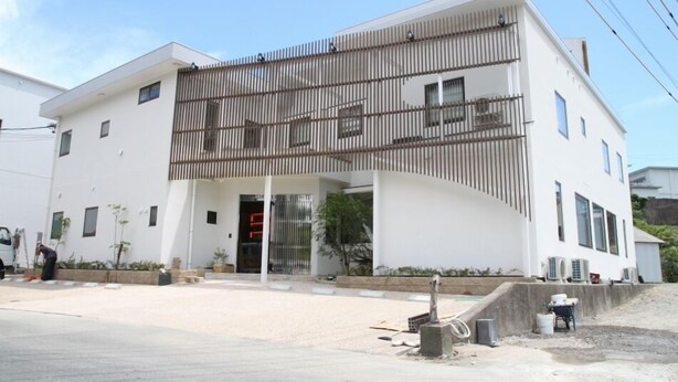A modern building with a white facade, a covered entrance, and a balcony. - Maruzen Ryokan (Toba)