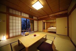 Una habitación japonesa tradicional con suelo de tatami, una mesa baja y puertas correderas.