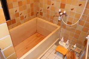 Una bañera de madera con un revestimiento de azulejos y un taburete pequeño de madera.