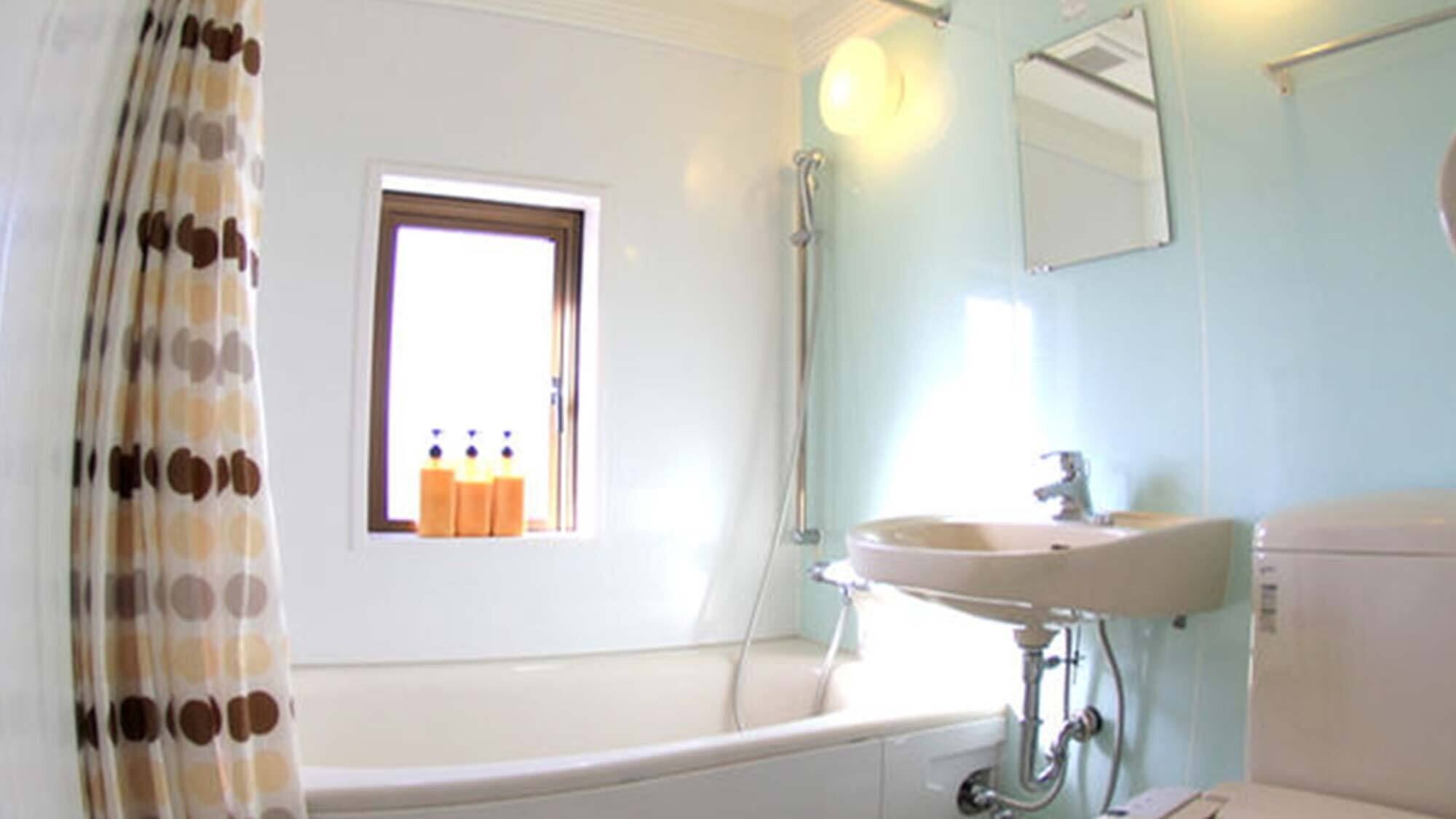 Ein Badezimmer mit Badewanne, Waschbecken und einem Fenster mit Flaschen auf dem Sims.