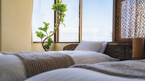 Een slaapkamer met twee bedden, een raam met uitzicht en een plant.