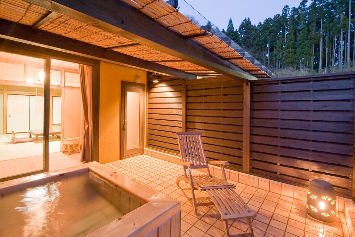 Un espace avec un bain à remous, une terrasse en bois, une chaise et une petite table.