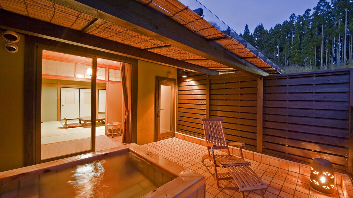 Eine Holzterrasse mit Whirlpool, einem Sessel und einer Laterne.